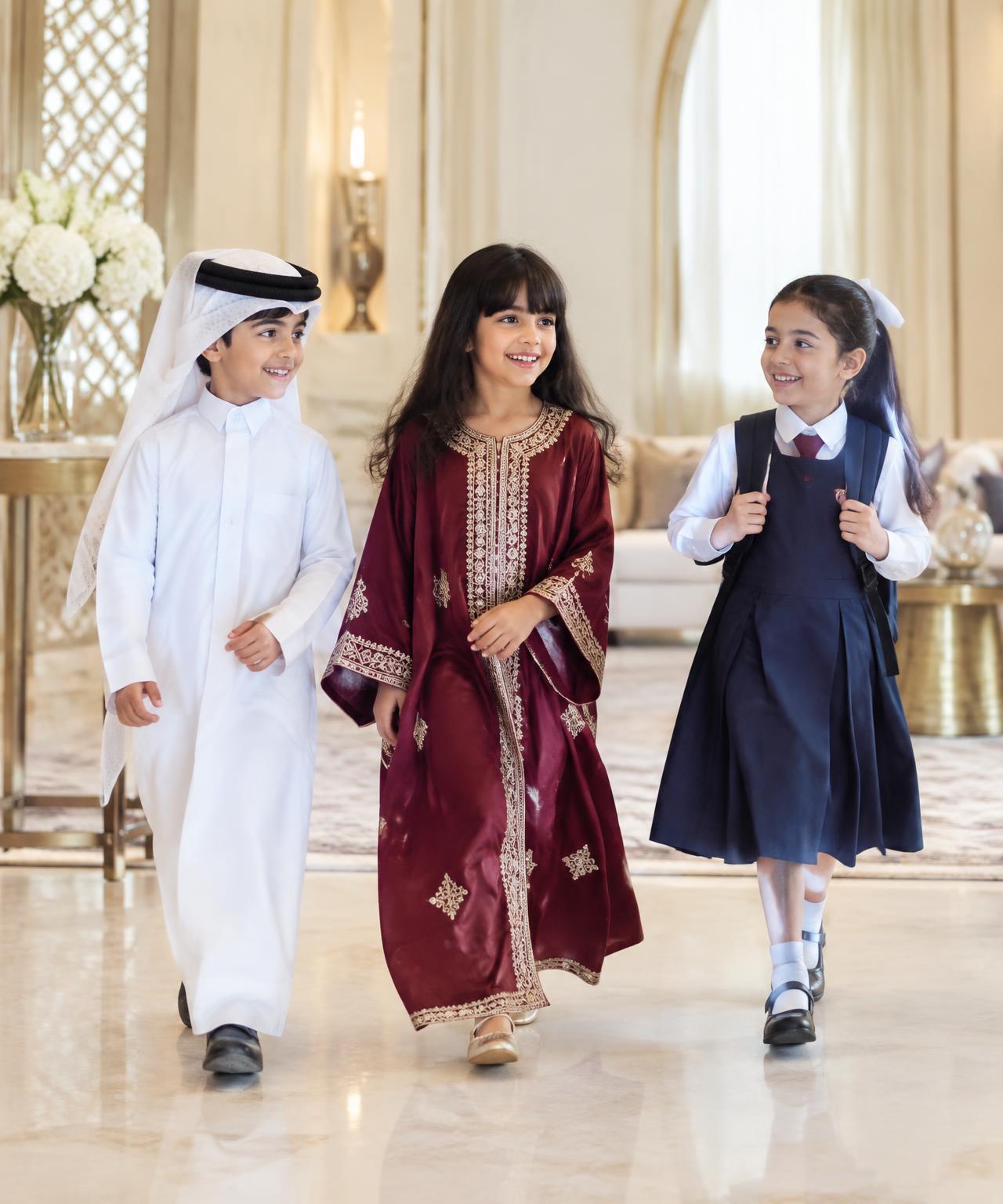Children walking together in Qatari dress and school uniform